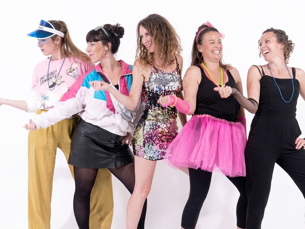 Un groupe déguisé danse devant le fond blanc du studio pendant le tournage d'un clip