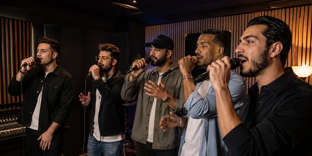 Cinq amis chantent ensemble au micro dans le studio d'enregistrement, pour un EVG à Paris