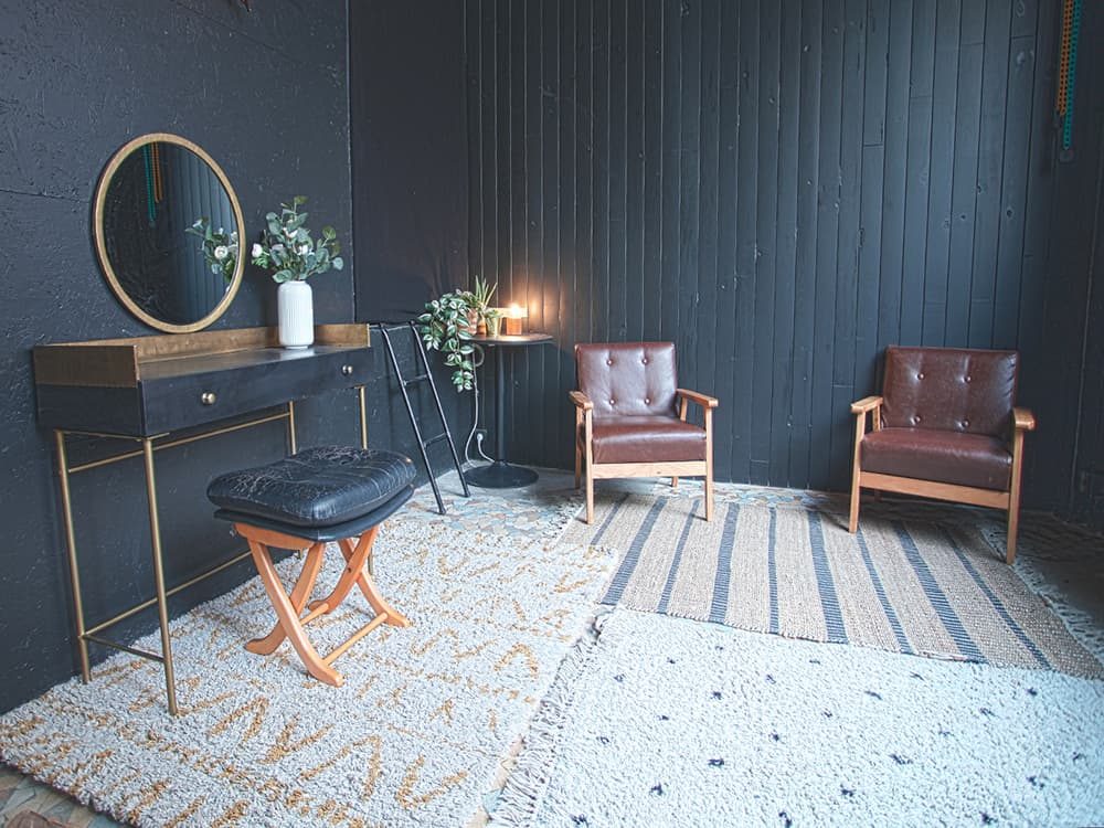 La loge du studio : coiffeuse en laiton, miroir rond, fauteuils en cuir et tapis