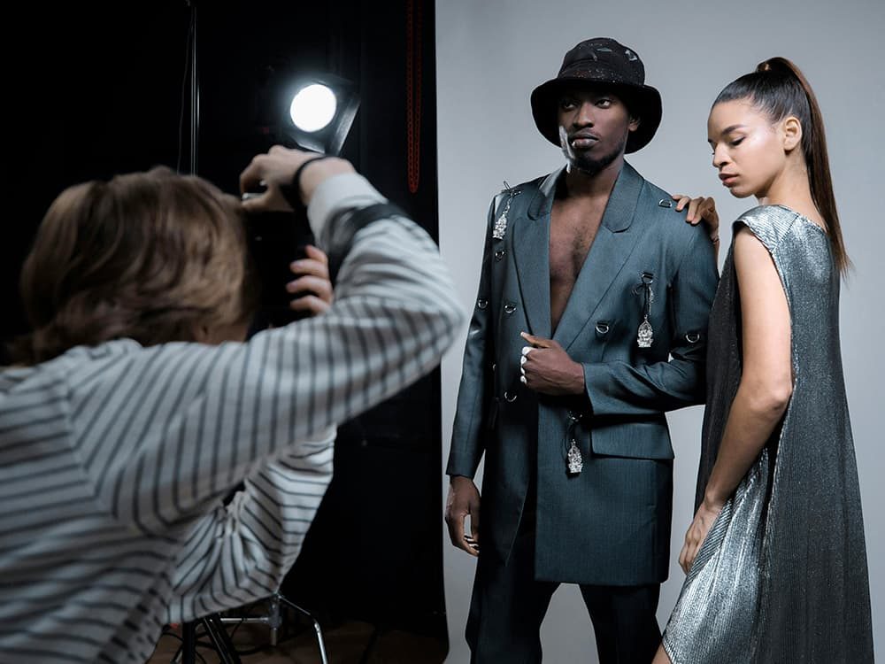 Le photographe du studio, de dos, en train de shooter deux personnes sous les projecteurs